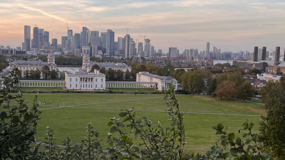 A view of Greenwich Park in early morning, with the Queen's House and the skyscrapers of Canary Wharf in the background