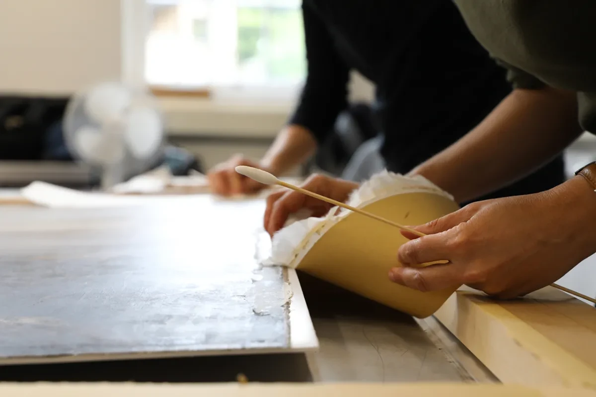 Japanese tissue paper is removed from the edge of a canvas during a conservation project