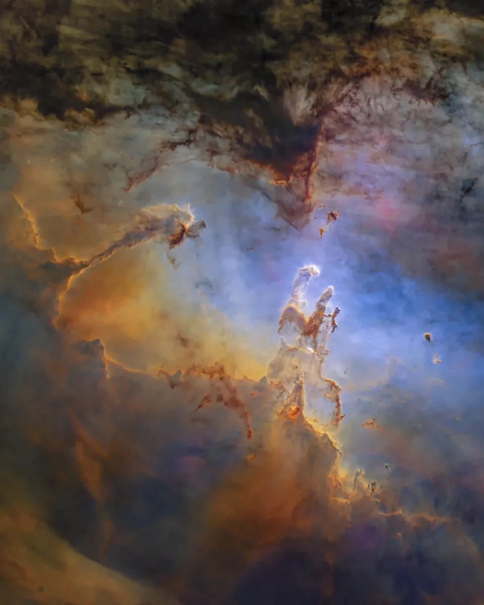 Image showing the nebula 'the pillars of creation', with clouds of gas in colours including gold and blue