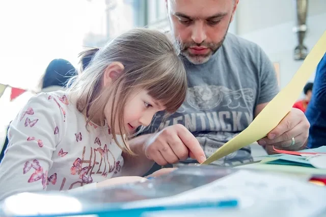 A parent and child looking at learning materials.