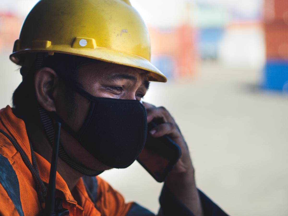 A masked seafarer on board is on the phone