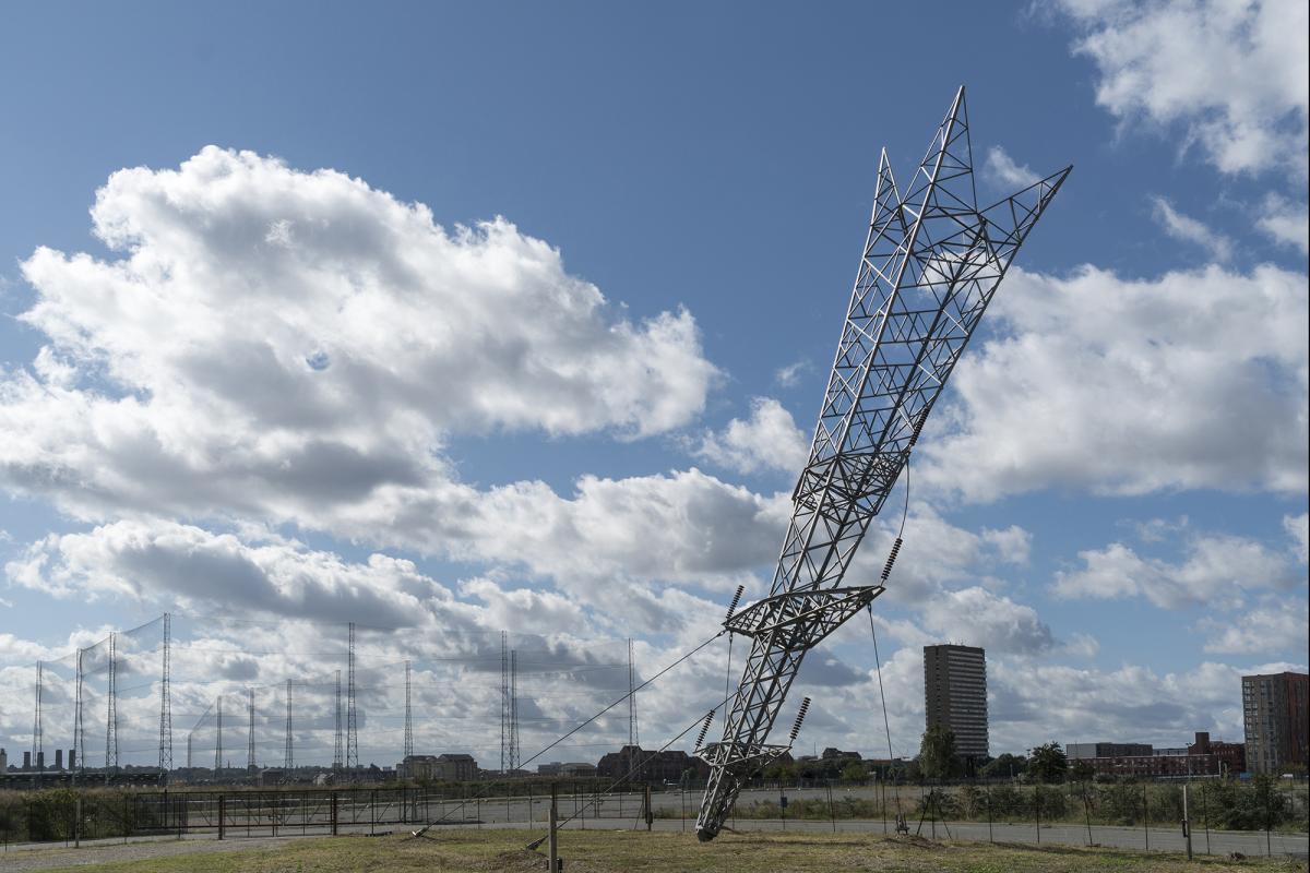 An inverted electrical pylon is stuck into the ground as part of an outdoor sculpture by artist Alex Chinneck