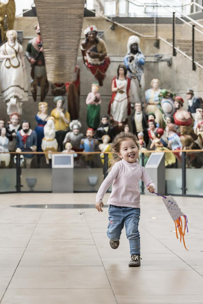 Toddler running in front of the figureheads 