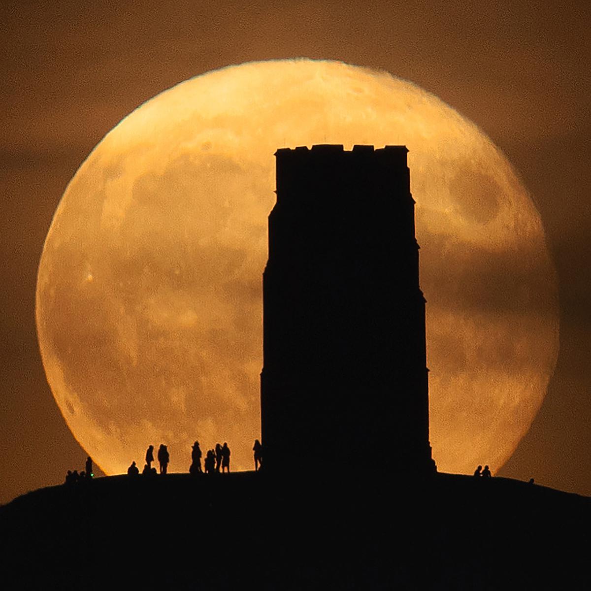 Image of Glastonbury Tor's shadow with moon double the size in the background