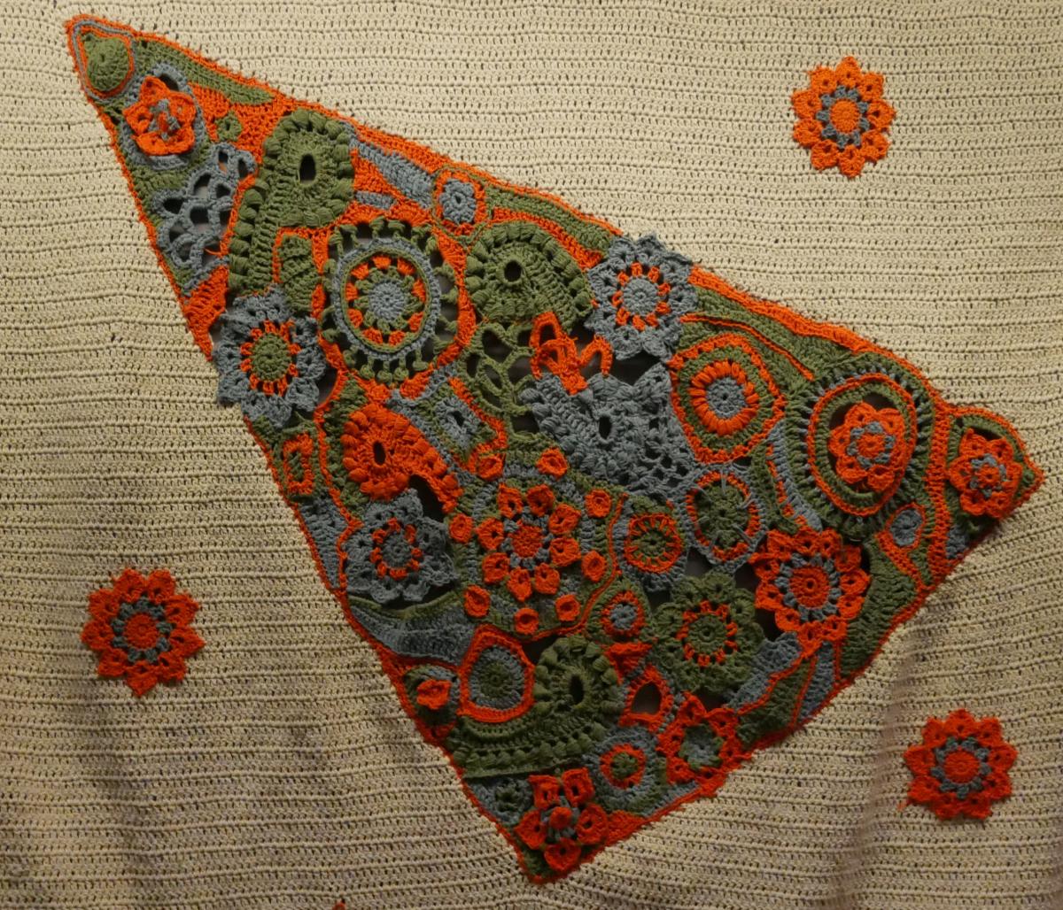 Orange blue and green crochet triangle as part of a kanga