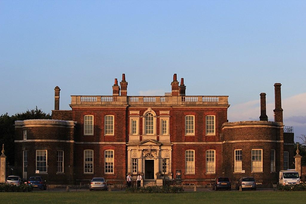 The Ranger's House in Greenwich Park at sunset, with the historic house's red brick and white framed windows lit up in the evening sun