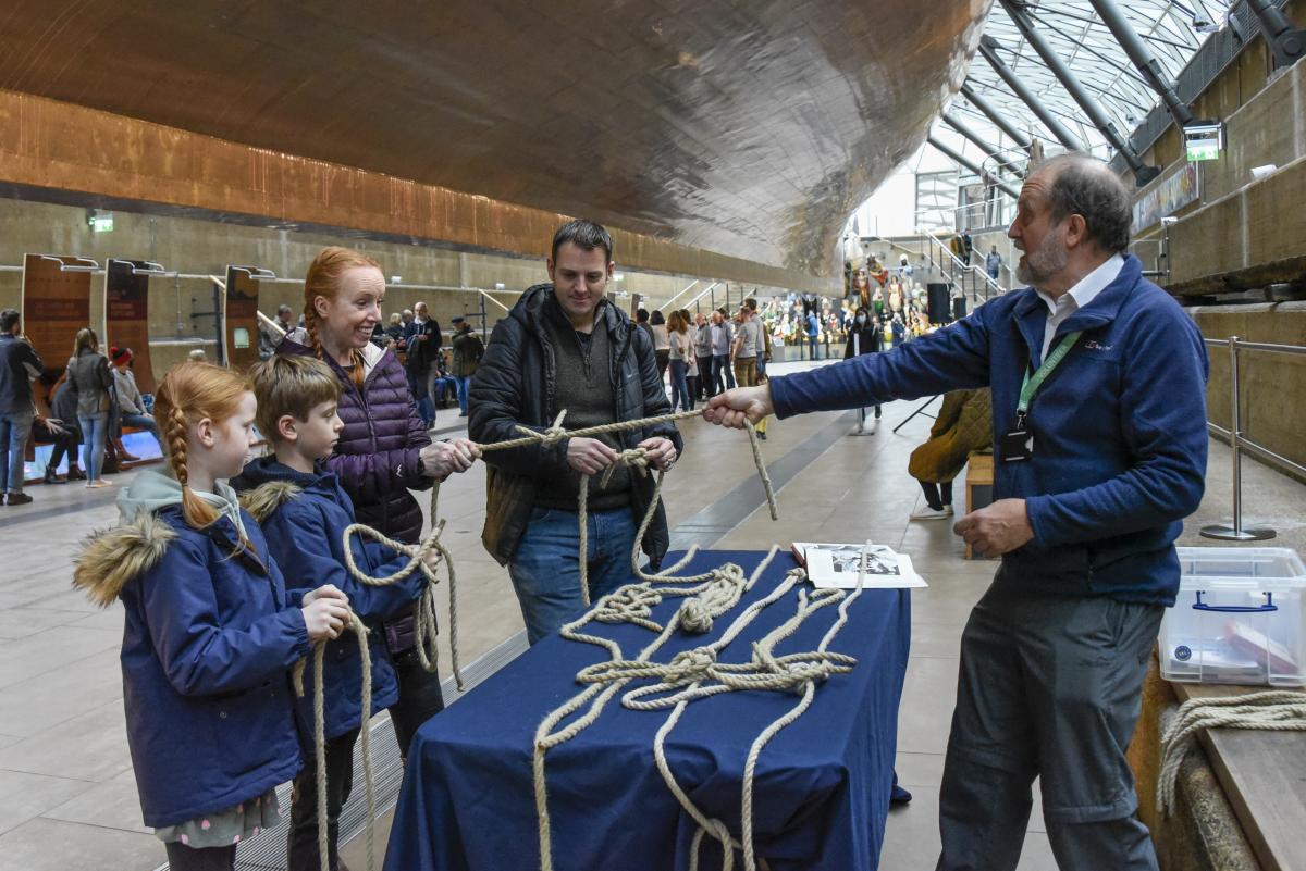 a man wearing a blue jumper tugging on a rope with a woman wearing a pink stripey top