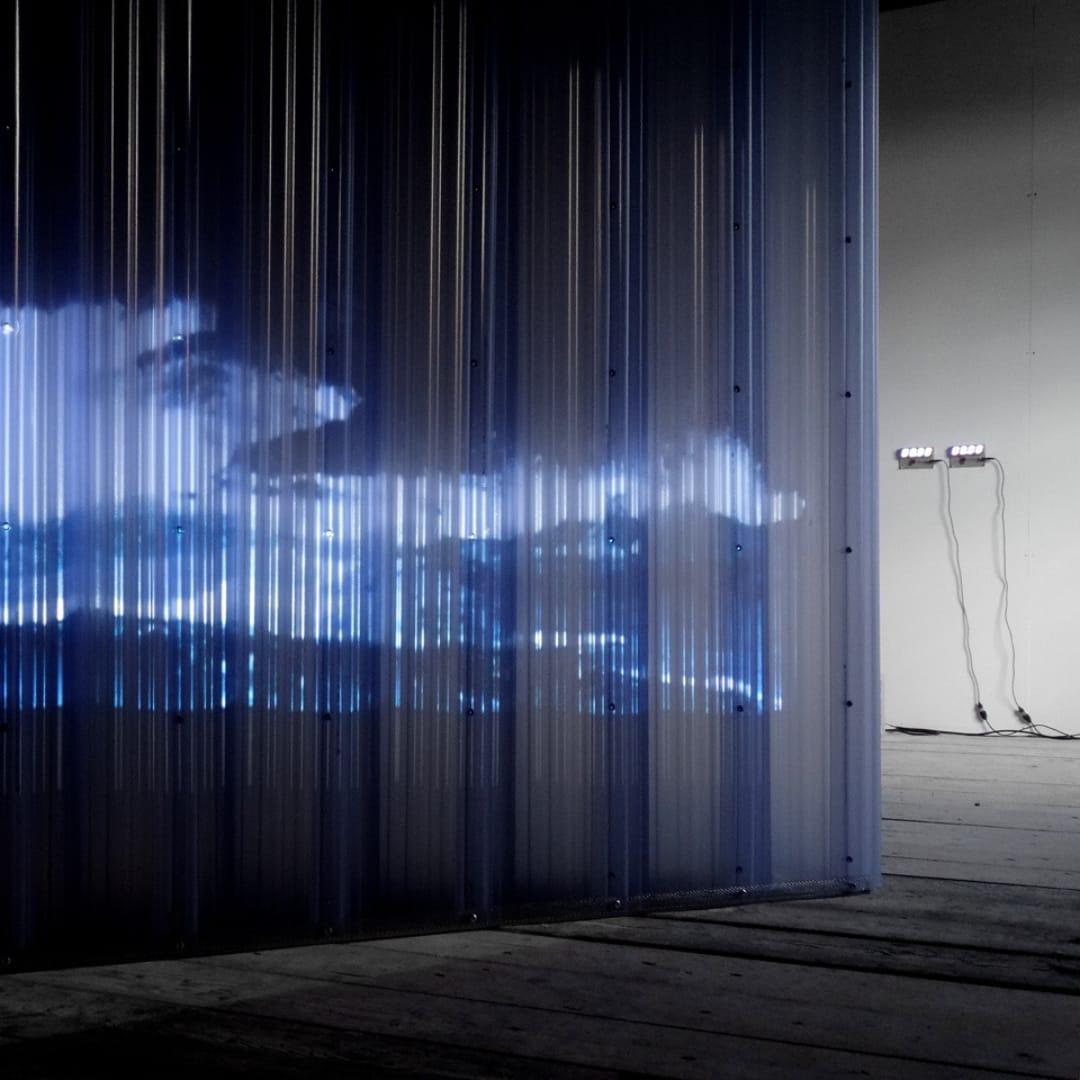 A digital concept for a light installation in a gallery. Tubes of blue plastic are installed in a bare space, with light animation playing across the surface