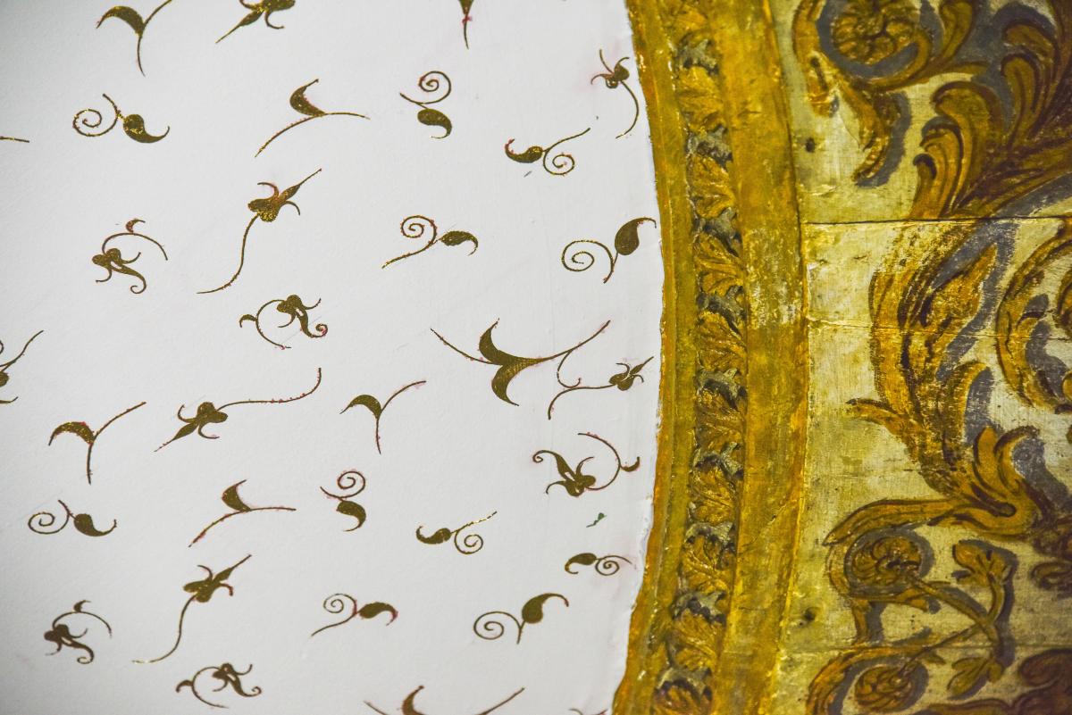 A close up view of the ceiling decoration in the Great Hall of the Queen's House. Contemporary gold leaf detailing on the left complements the historic plasterwork on the right