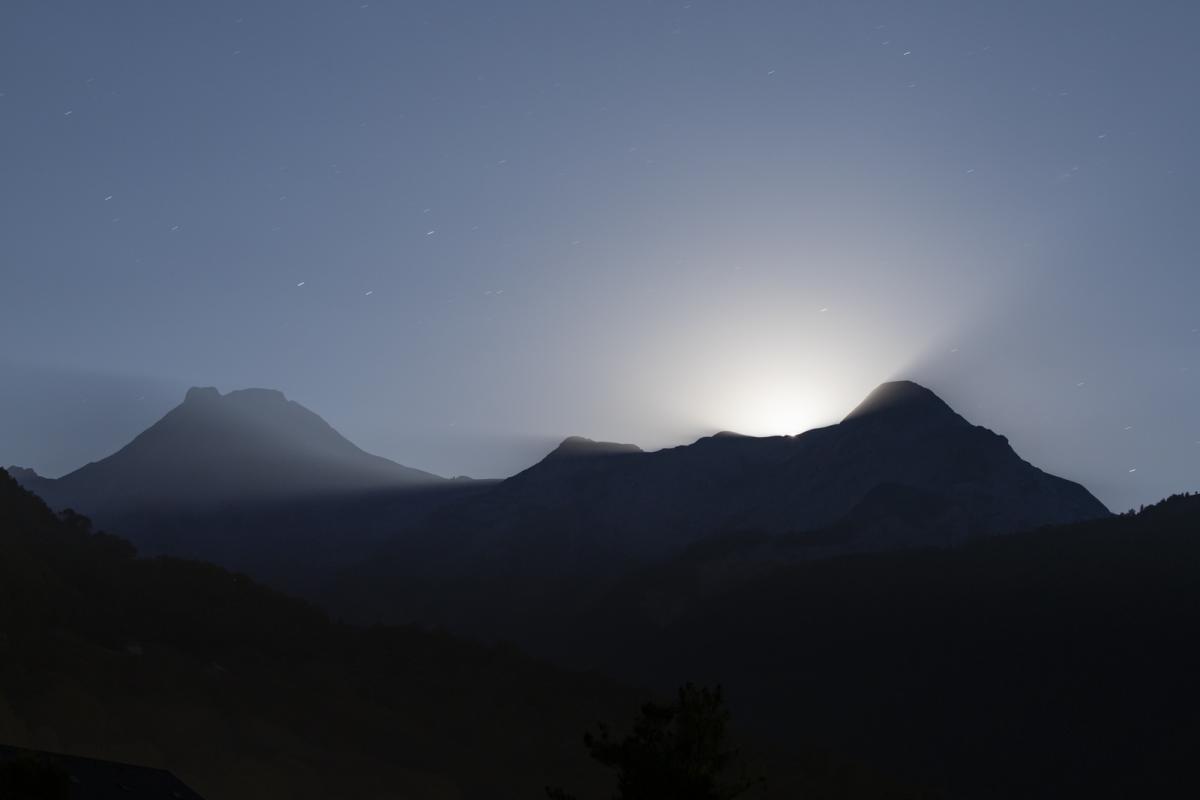 Full Moon rising over silhouette of mountains