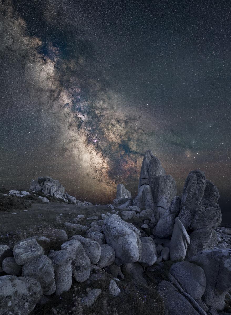 Image showing a rock formation in the foreground with the Milky Way diagonal in the background in grey and white tones