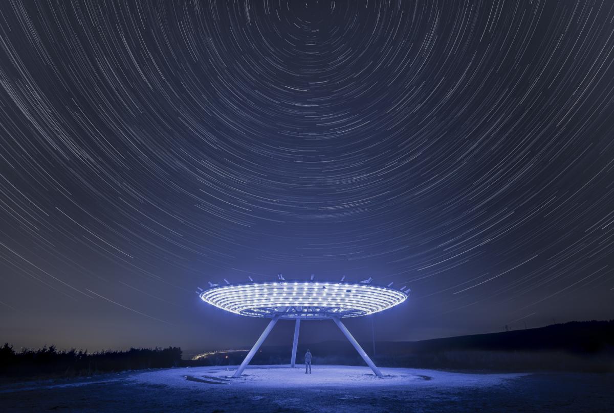 Elevated disk sculpture illuminated by LED lights