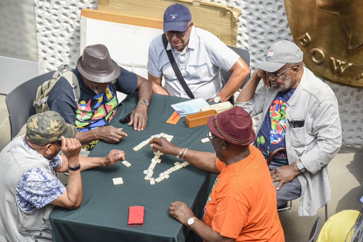 Image of five men around a table playing dominos