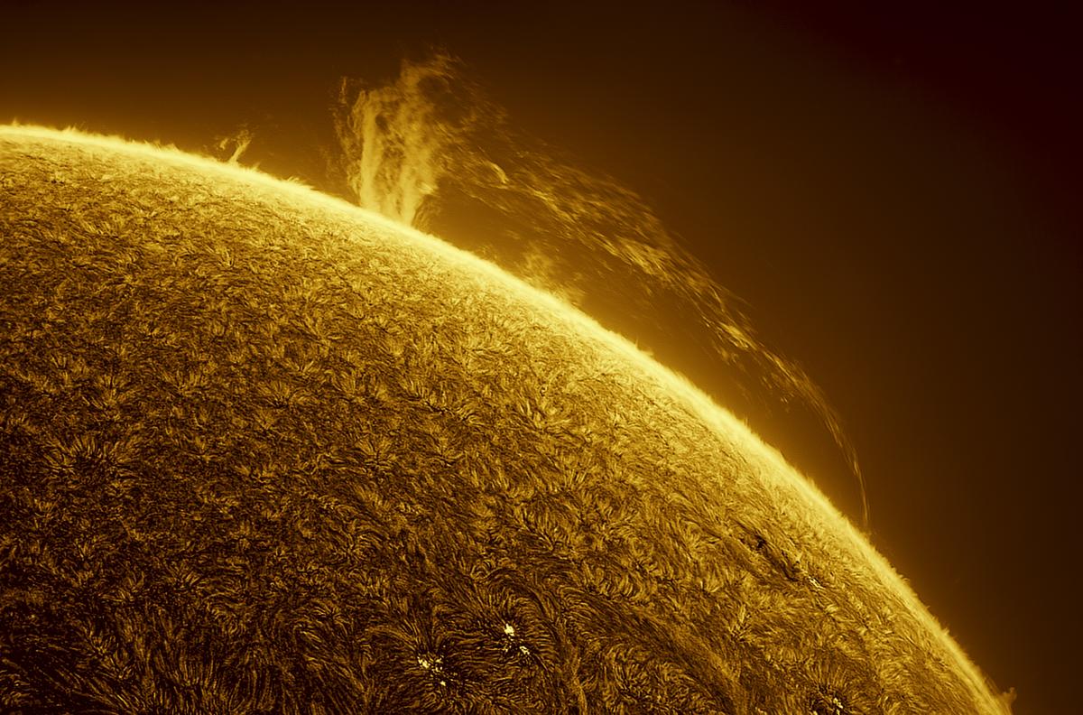 Image of a small proportion of the Sun, which is lit up in golden yellow at the surface and moves to darker colours away from the surface. A golden plume of a coronal mass ejection is coming out of the Sun and flowing parallel to it.