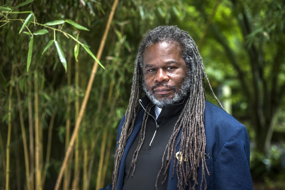 man standing in front of greenery smiling