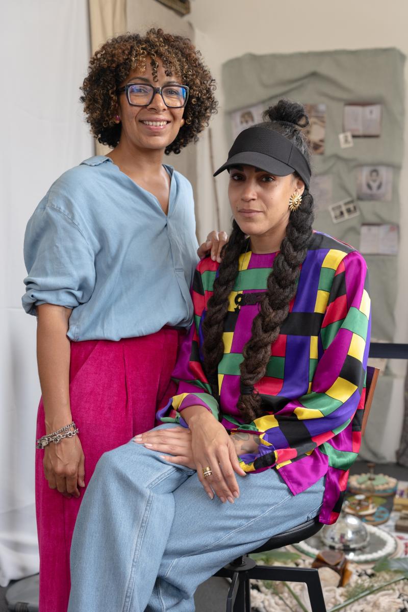 Two artists wearing colourful clothing smile at the camera