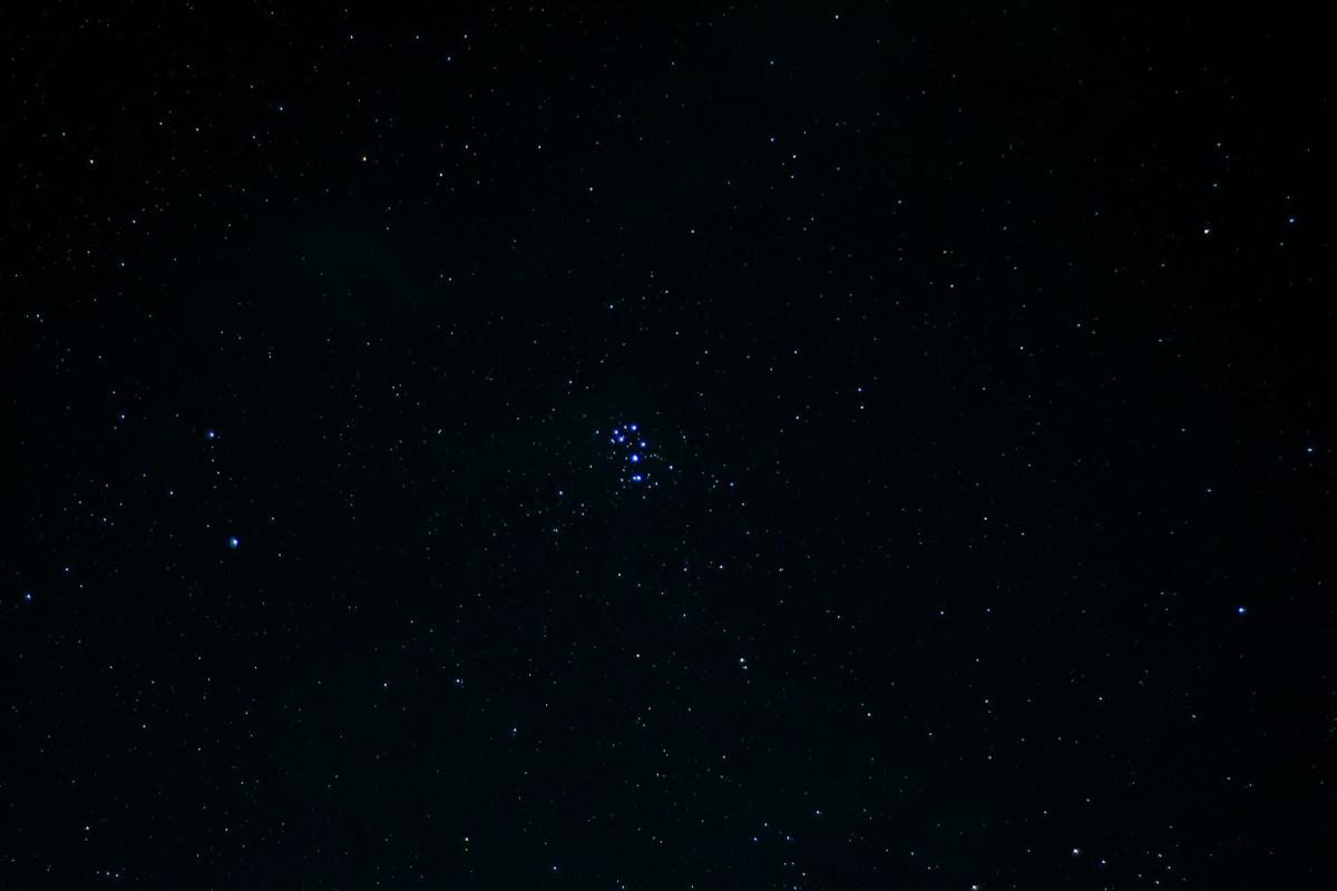 Image of dark black sky with bright cluster of blue stars in the middle