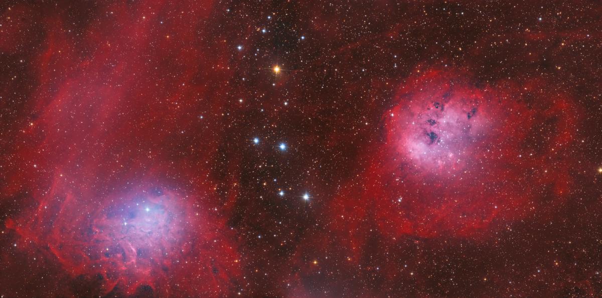 Image showing two nebulae next to each other in space, clouds and waves of gases and dust coloured in different shades of red, varying from deep reds to light pinks. The two nebulae are similar round shapes with light pink sections in the middle. Behind is a very starry sky hazed in a deep red