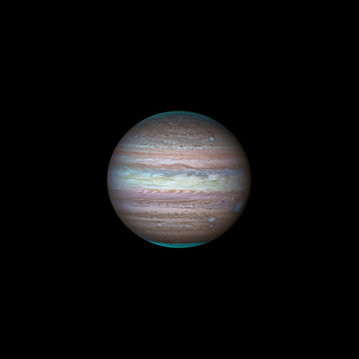 Telescope view of Jupiter using visible and methane band filters, which reveal bright blue-green bands across the planet's surface and the polar regions