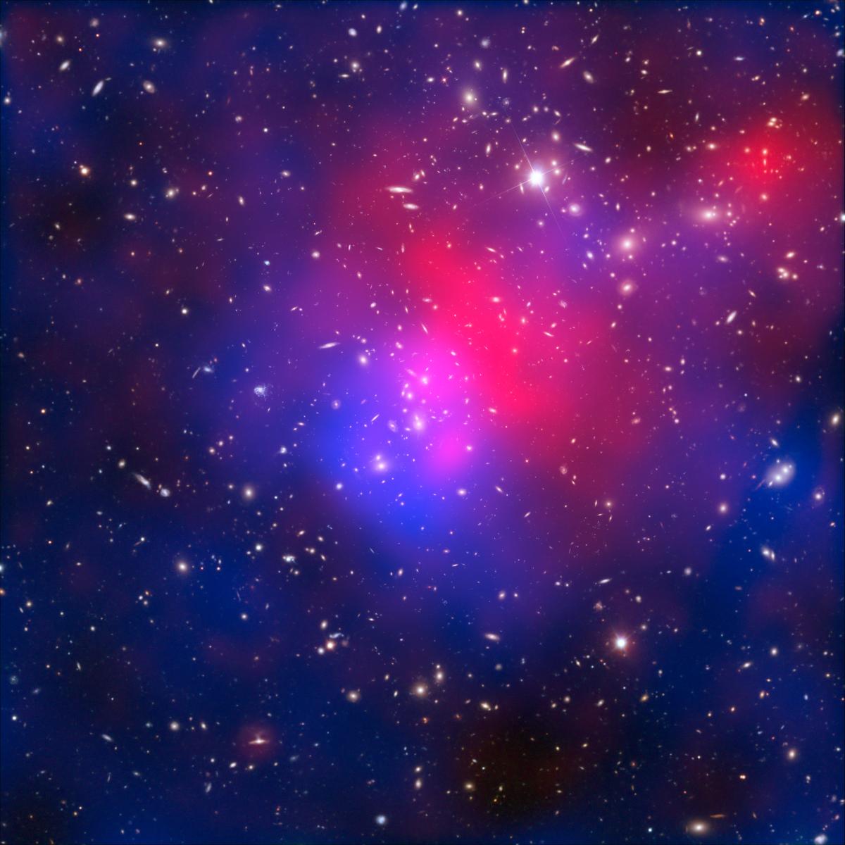 A pinkish blue haze in the centre of an inky night sky. This is visible light exposures of galaxy cluster Abell 2744 taken by the NASA/ESA Hubble Space Telescope and the European Southern Observatory’s Very Large Telescope