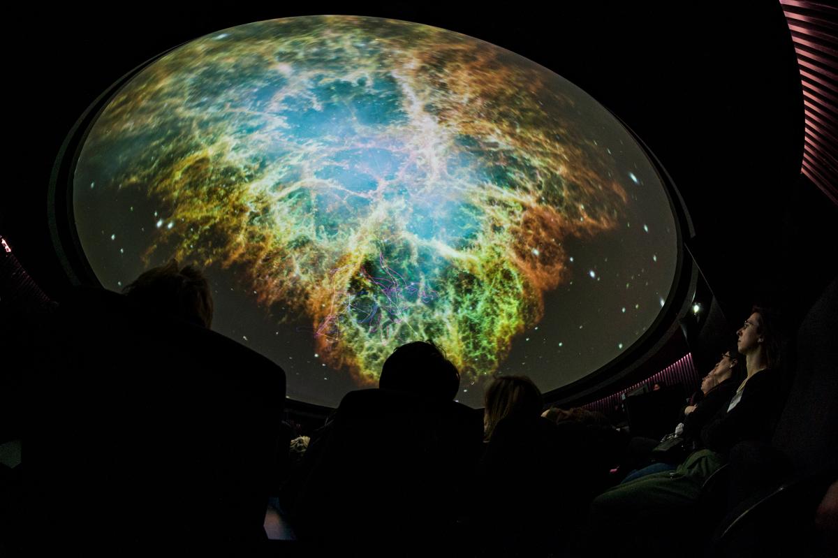 The inside of the Peter Harrison Planetarium during a show, with the dome filled with an image of a distant nebula