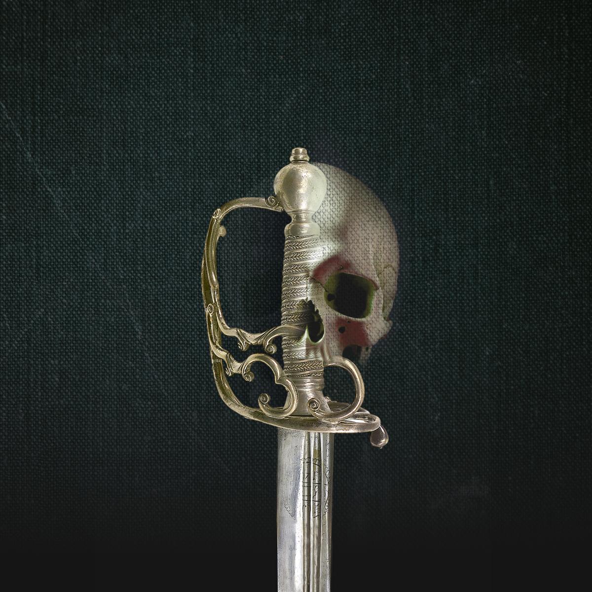 The gold hilt of a sword against a dark fabric background. The outline of a human skull has been digitally superimposed on to the right side of the hilt, creating an unsettling central motif 