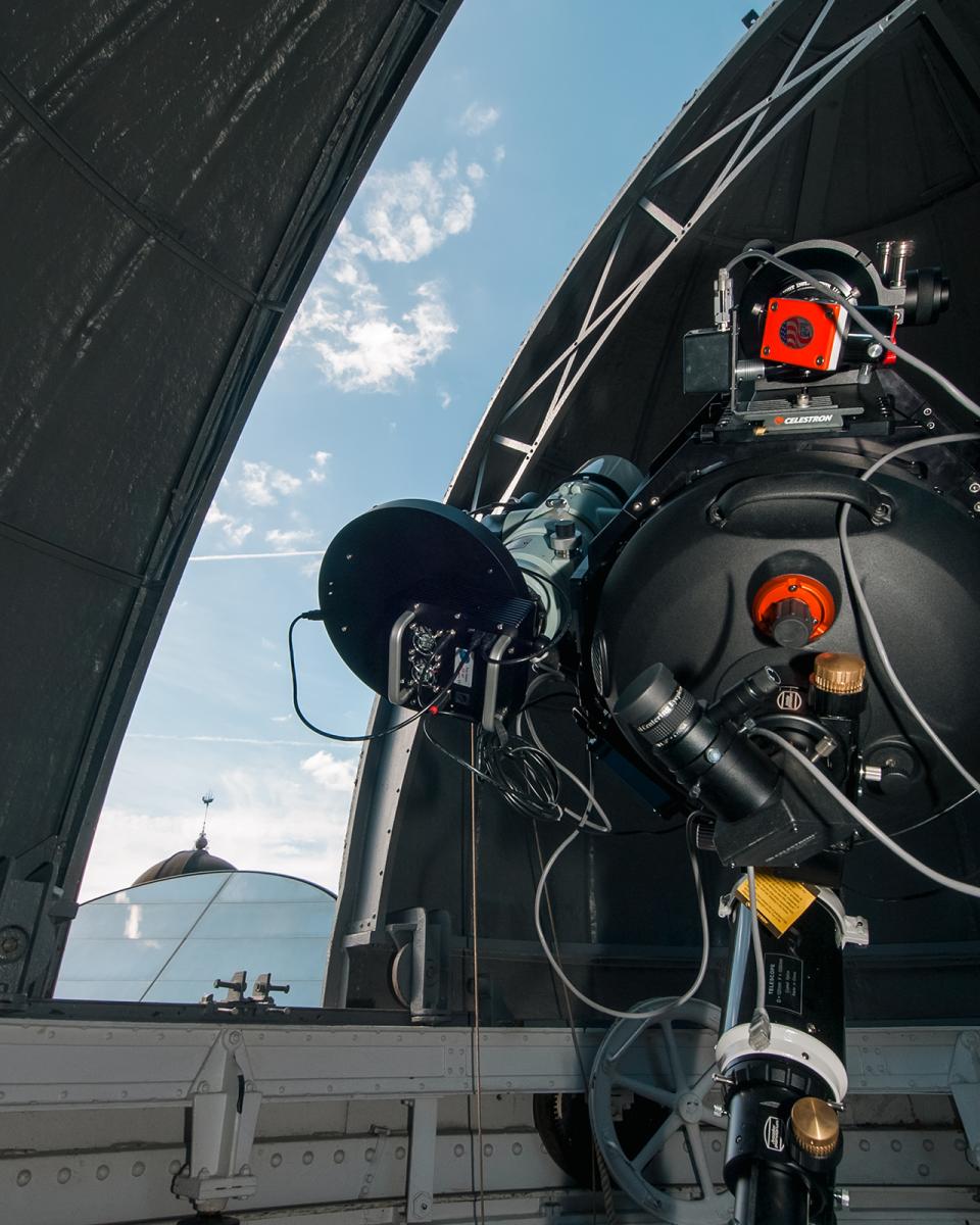 The Annie Maunder Astrographic Telescope at the Royal Observatory. The Observatory's domed roof is partially open, allowing a view of a clear blue sky