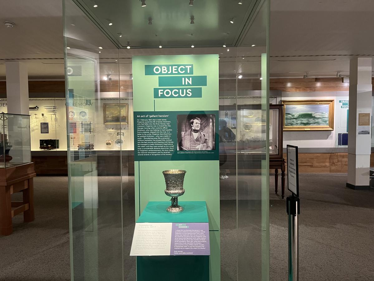 Photo of a glass display case in a museum gallery with the title 'Object in Focus' and an engraved cup on a stand with information text around it