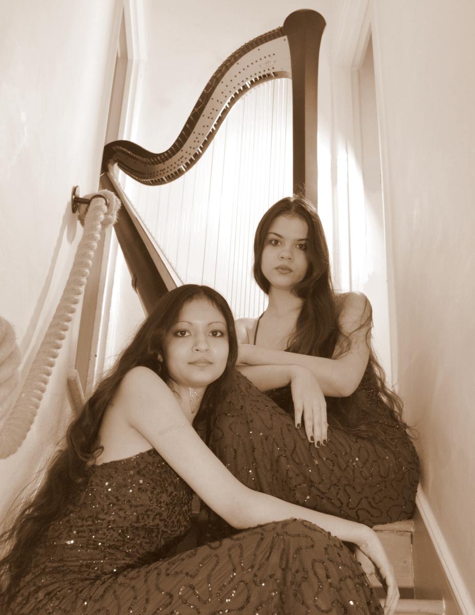 Photograph of harpists Catherine and Elizabeth Rajhans with a harp behind them