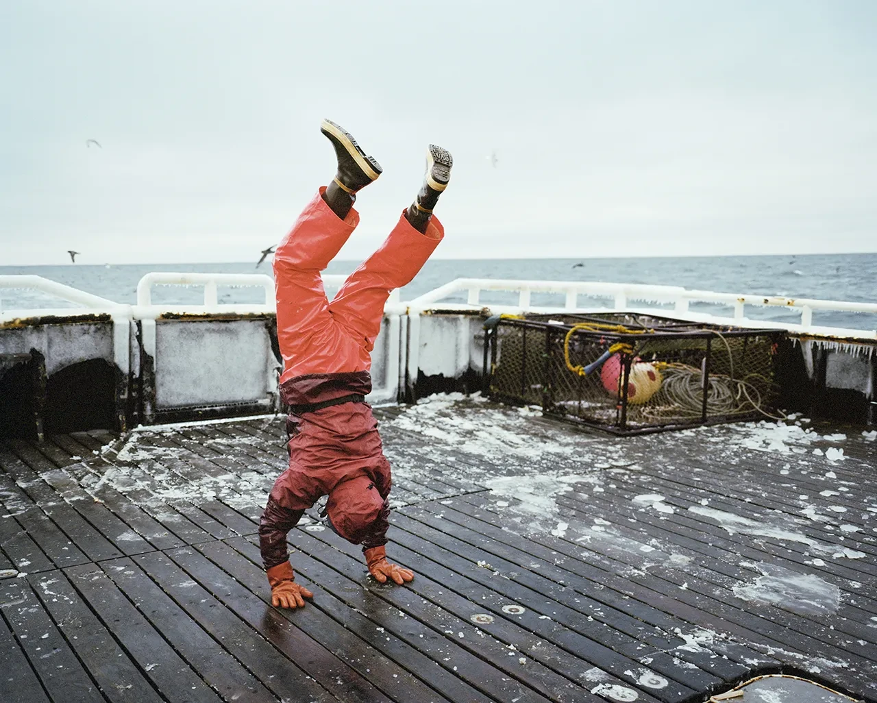 Photo of a person doing a handstand on the deck of a boat at sea