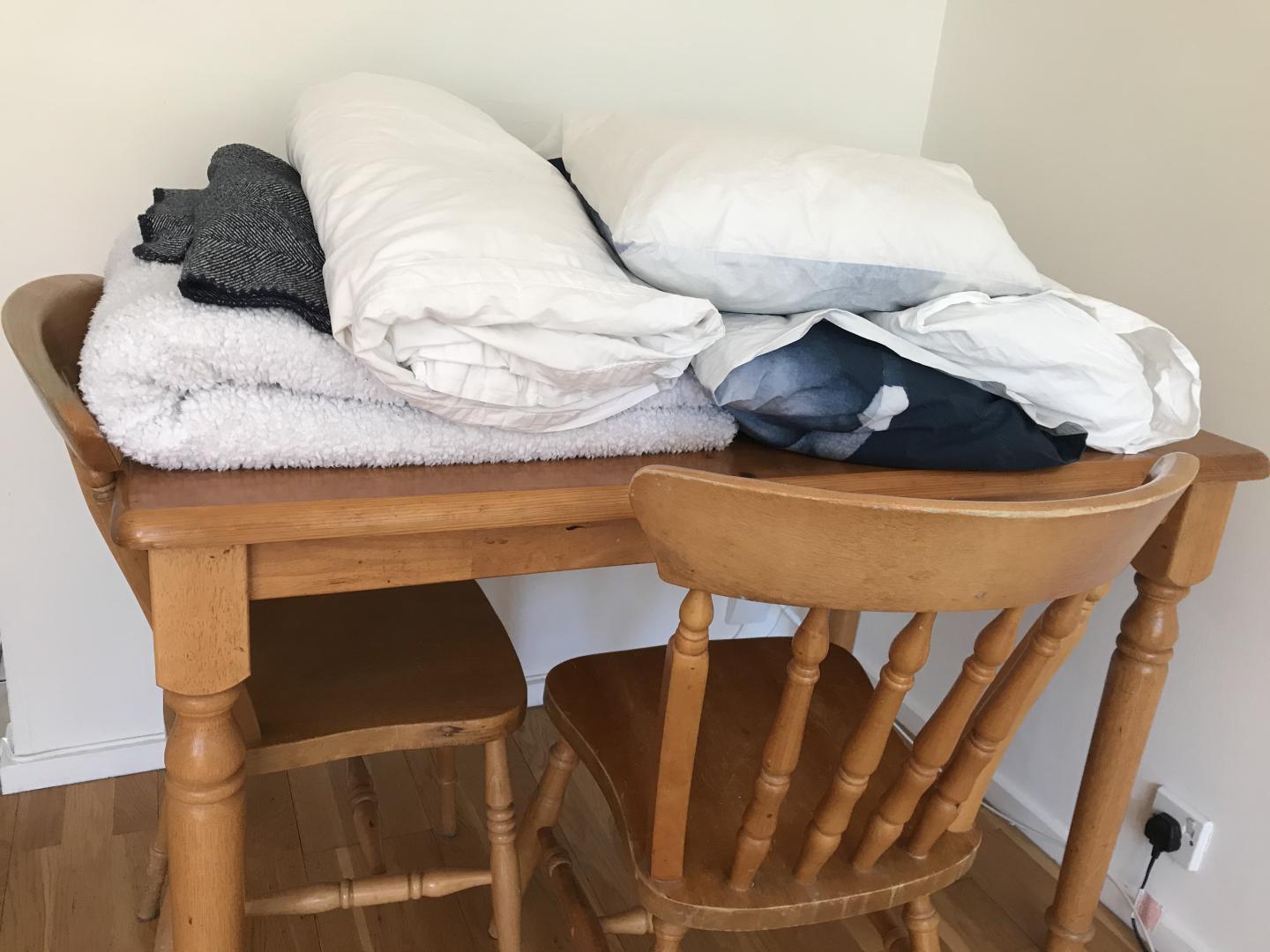 table and chairs with folded blankets and cushions on top.