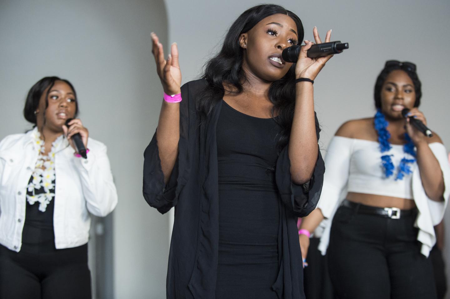 Three people performing on mic