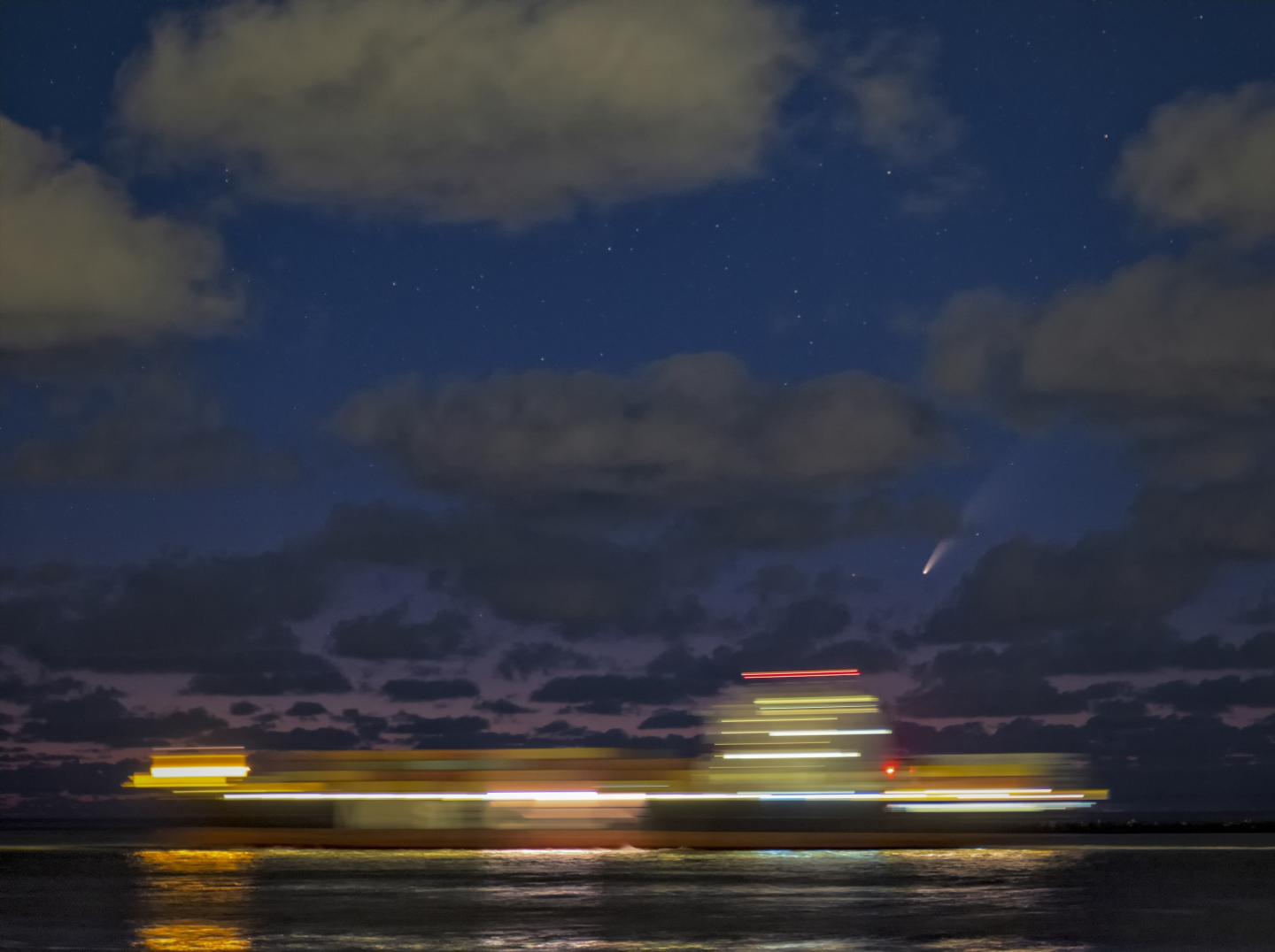 Ship sailing at night with NEOWISE comet overhead