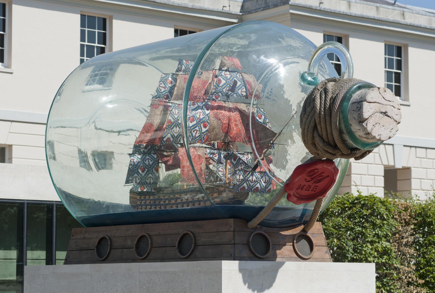 Large stoppered bottle with a ship inside, sitting on a plinth