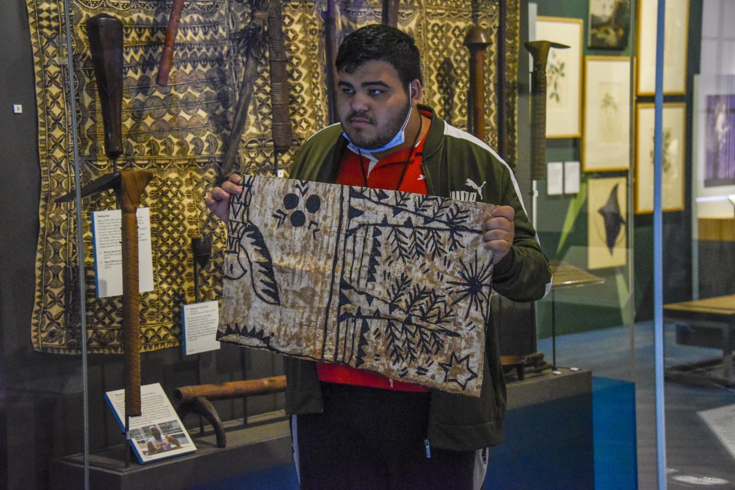 A young person holding up tapa