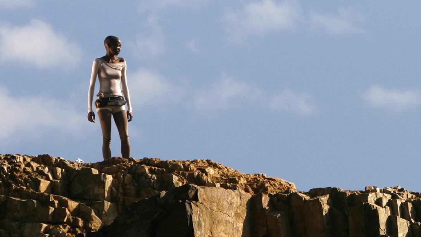 An image of a black woman standing on a cliff edge