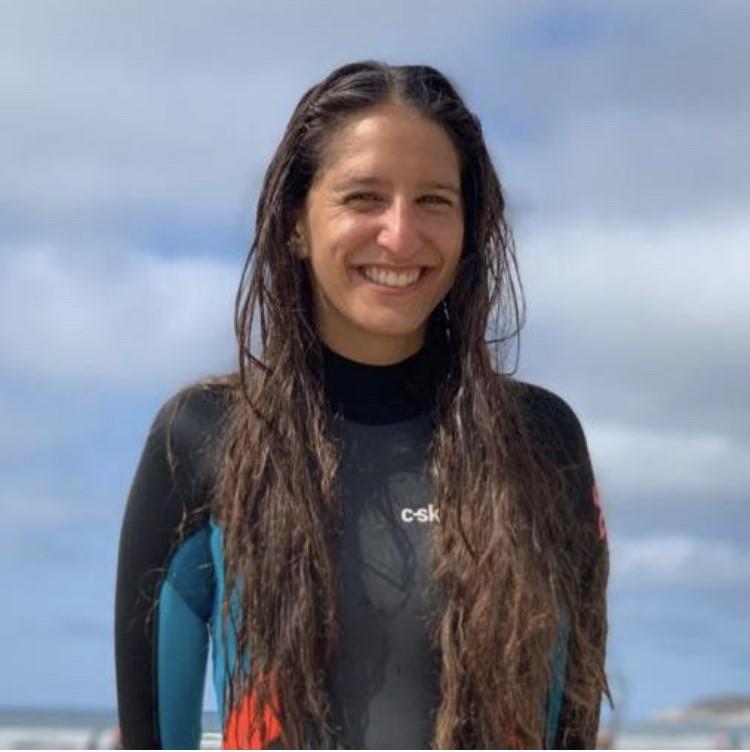 A top body shot of a woman in a wetsuit with long dark hair, sky in the background