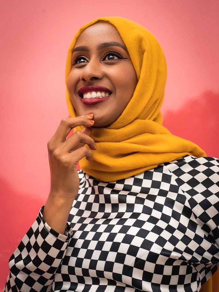 photo of a women smiling with yellow head scarf and check top