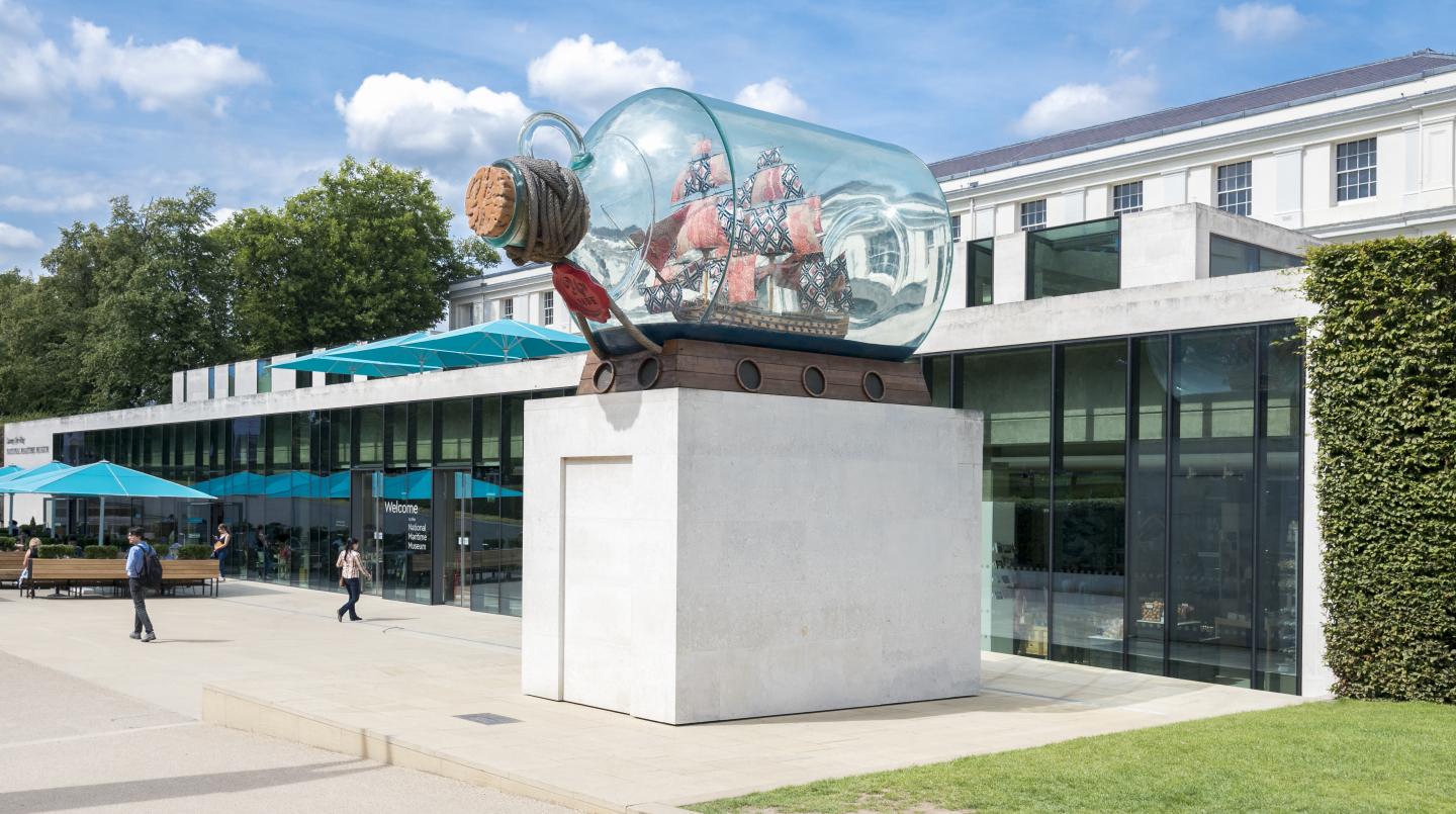 An installation of a model ship inside a large glass bottle in front of the National Maritime Museum