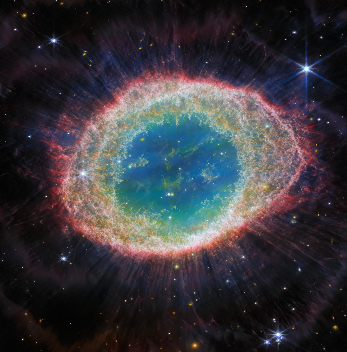 Detailed image of the Ring Nebula, a circle of blue gas surrounded by yellow, then red. 