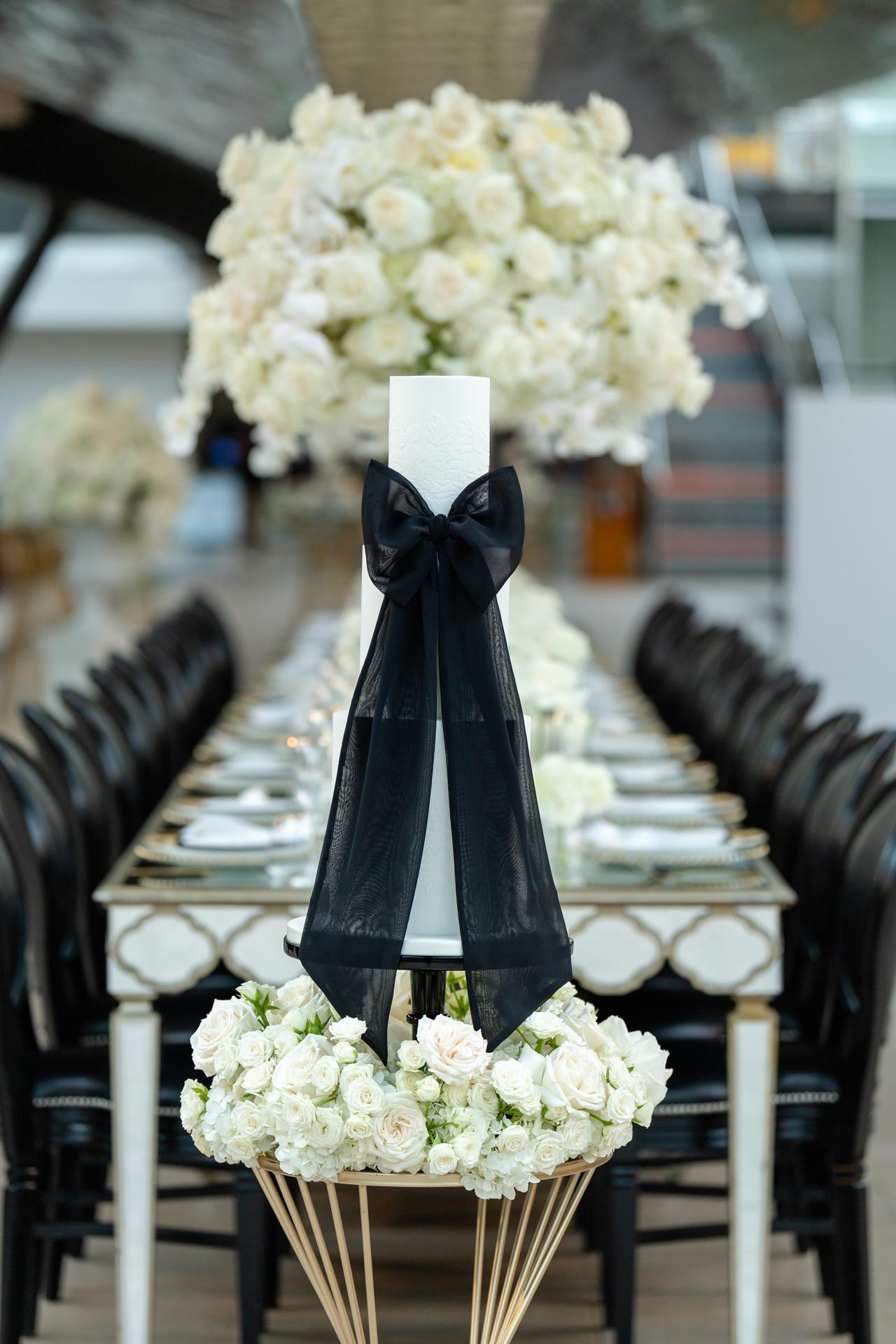 white wedding cake on display in dry berth with a velour black bow around it