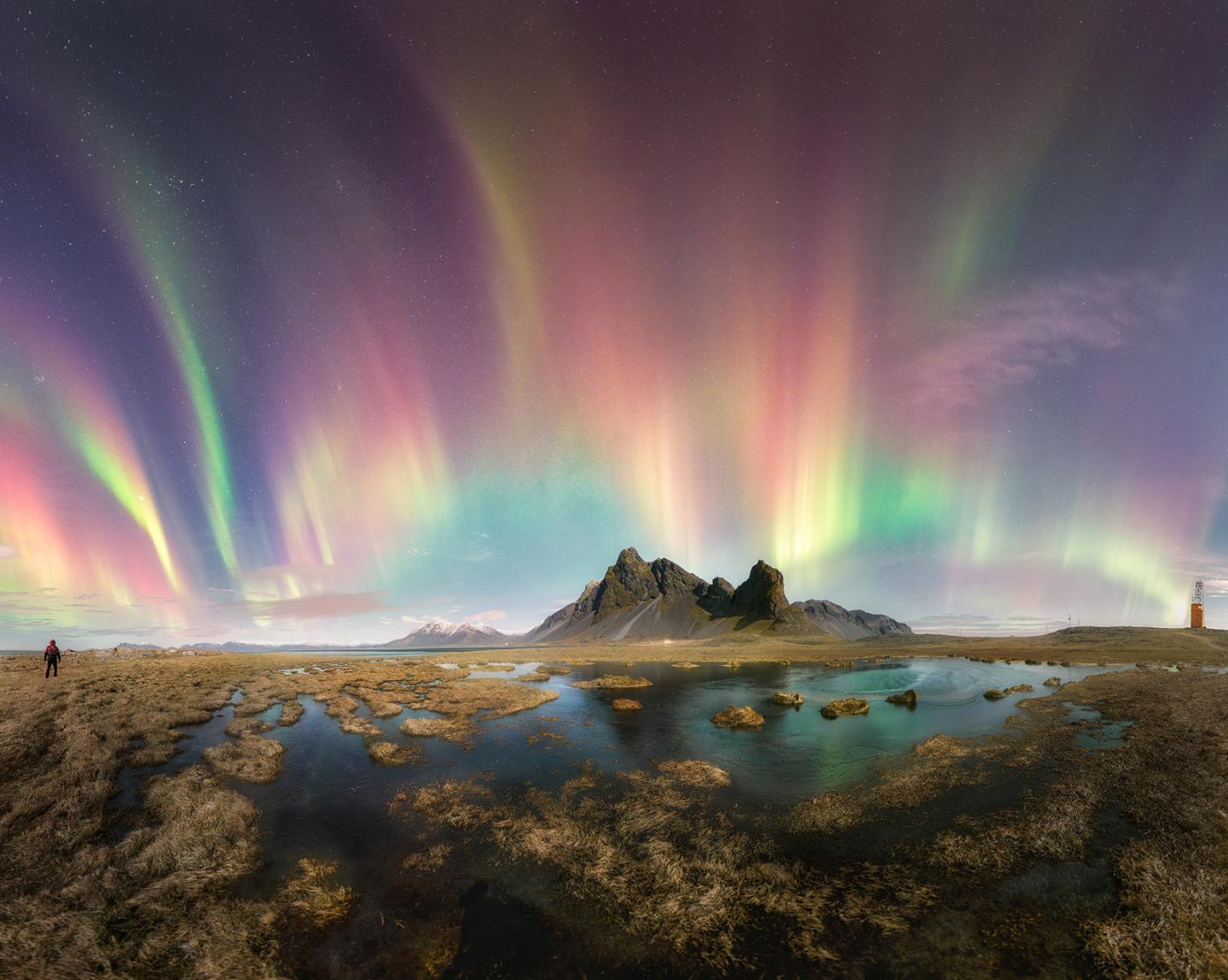 Red, green and purple aurorae stretch above a mountain