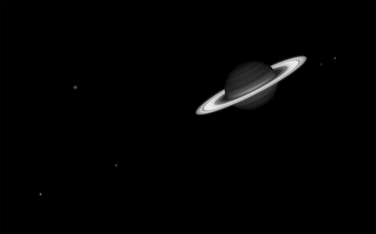 Black and white telescope view of Saturn and five of its moons