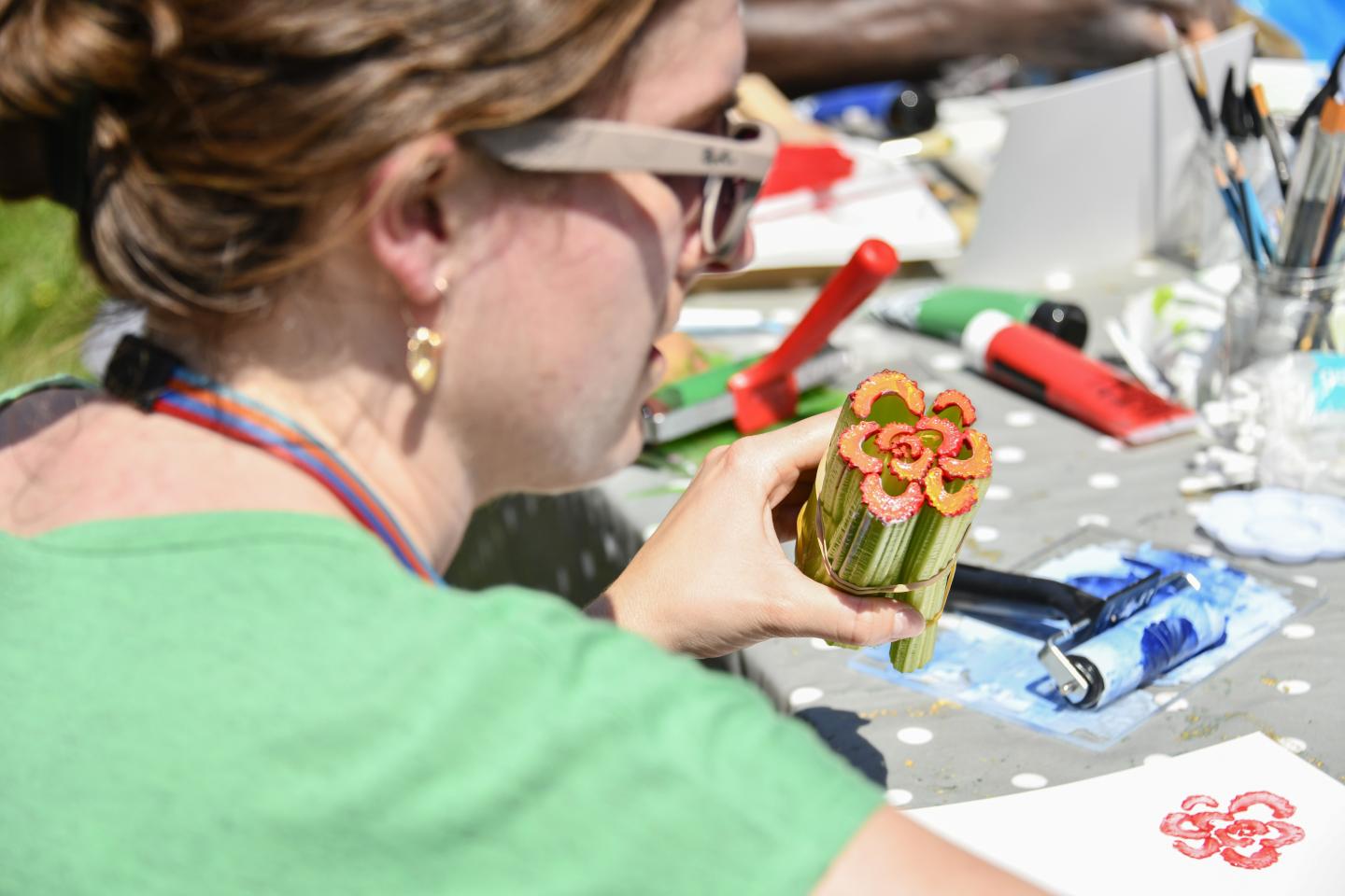 person holding celery stems in the shape of a flower with red paint