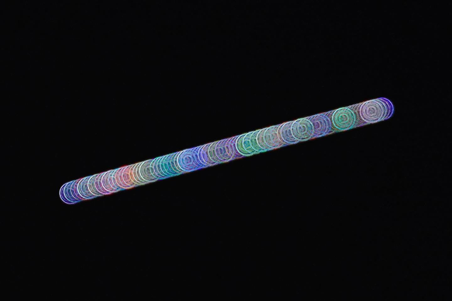 A diagonal strip of light against a dark background, made up of dozens of coloured spirals