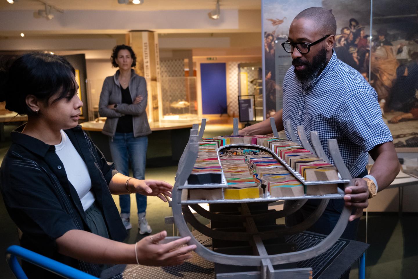 Professor Elgin Cleckley and Iana Ishrat install a model of a ship filled with colourful zigzag markers in the National Maritime Museum