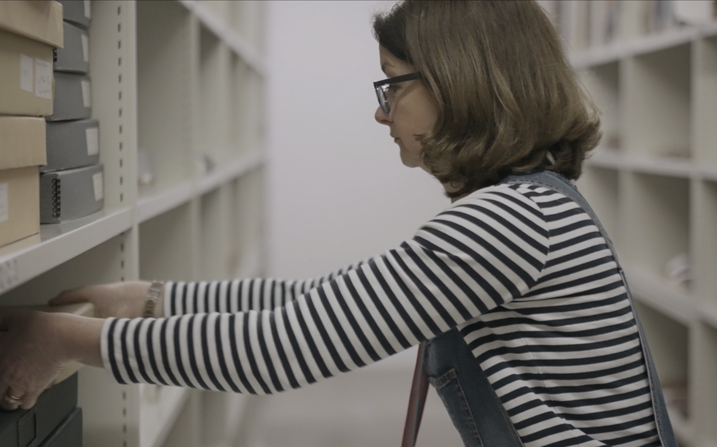 An Archives Assistant removes a box from a library shelf