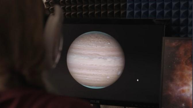 Photo showing back of person's head wearing headphones, looking at a computer screen with a photo of Jupiter on it with blue methane highlighted