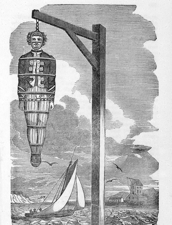 Black and white illustration of a pirate hanging in a gibbet cage. The body is strapped inside metal chains and hung from a wooden scaffold