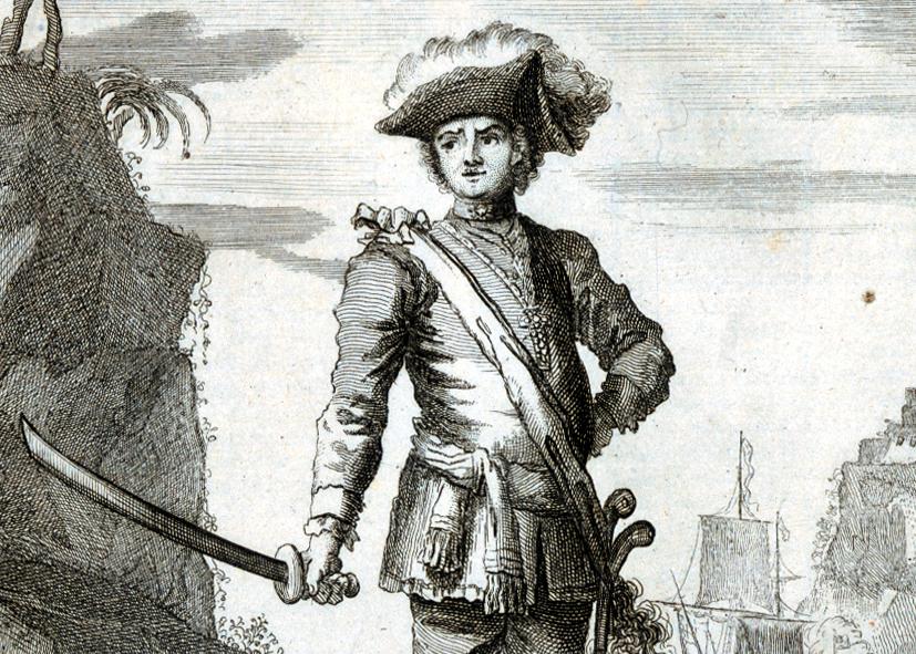 Historic illustration of the pirate Bartholemew Roberts. He is standing dramatically at the shoreline, holding a sword in his right hand and wearing a tricorn captain's hat